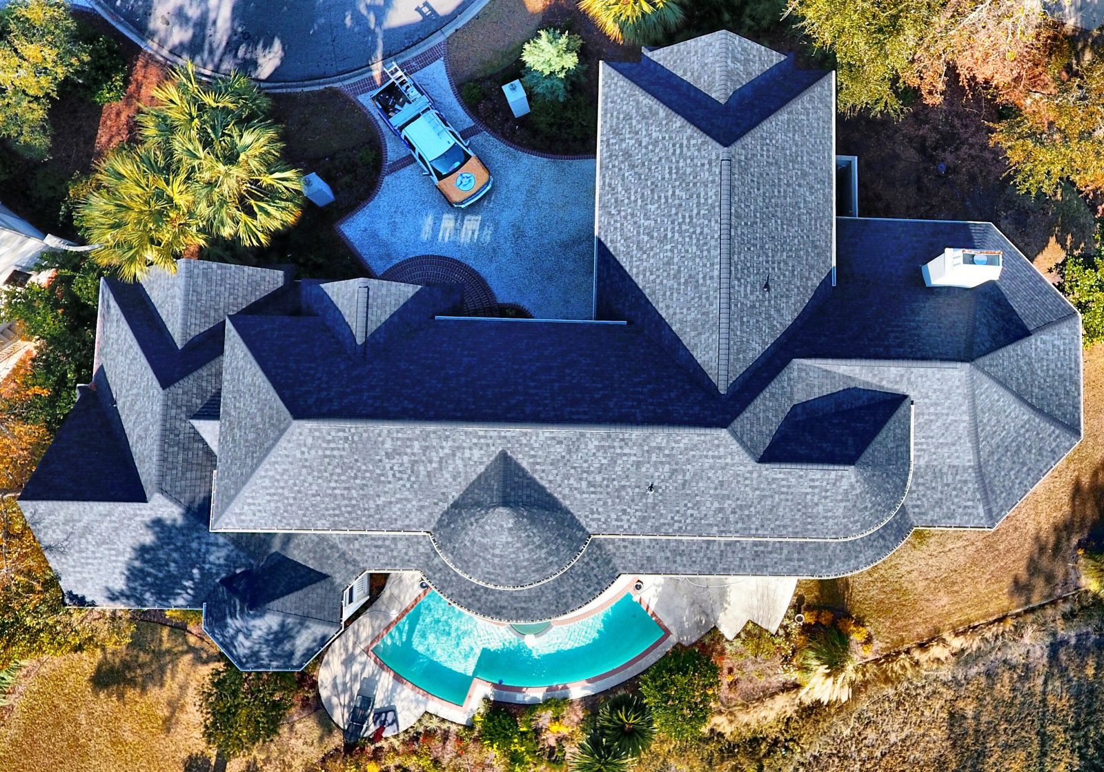Overhead drone photo of a large estate home with a pool and a new architectural shingle roof