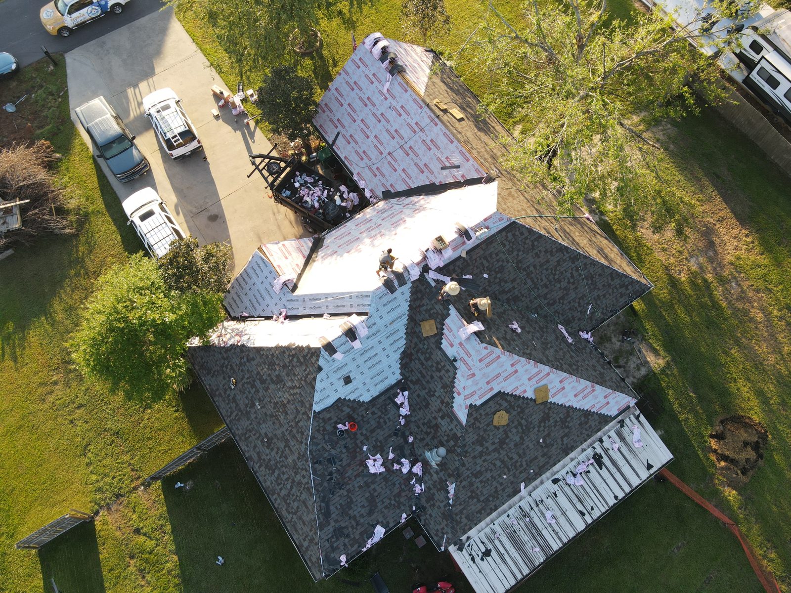 Aerial view of an Exterior Genie crew mid-installation, tearing off old shingles and laying synthetic underlayment on a Lexington SC home